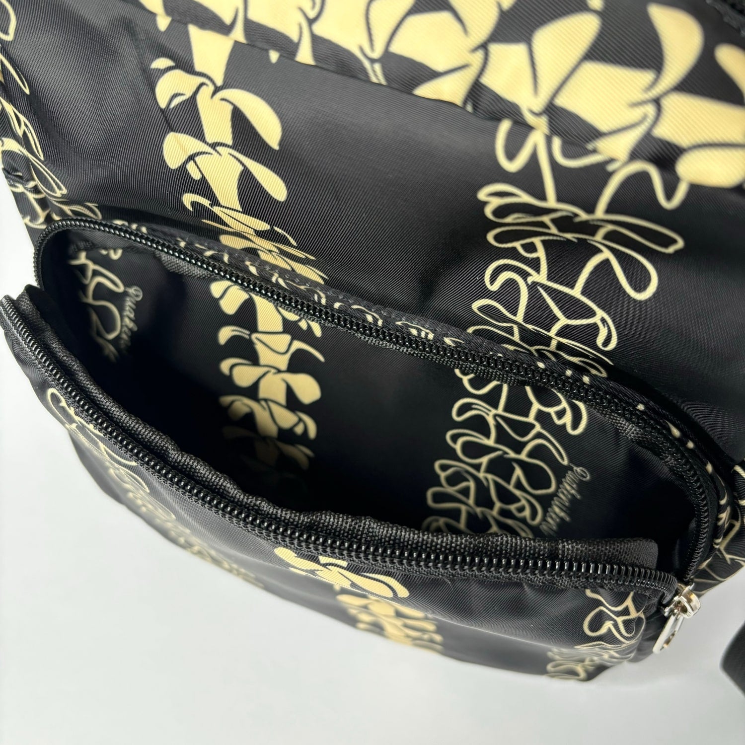 Crossbody bag by Puakenikeni Designs, in black with the best-selling pua kenikeni lei design, Kaulua; for women, moms, teenage girls, for travel and school Beige Lei Design close up of front pocket