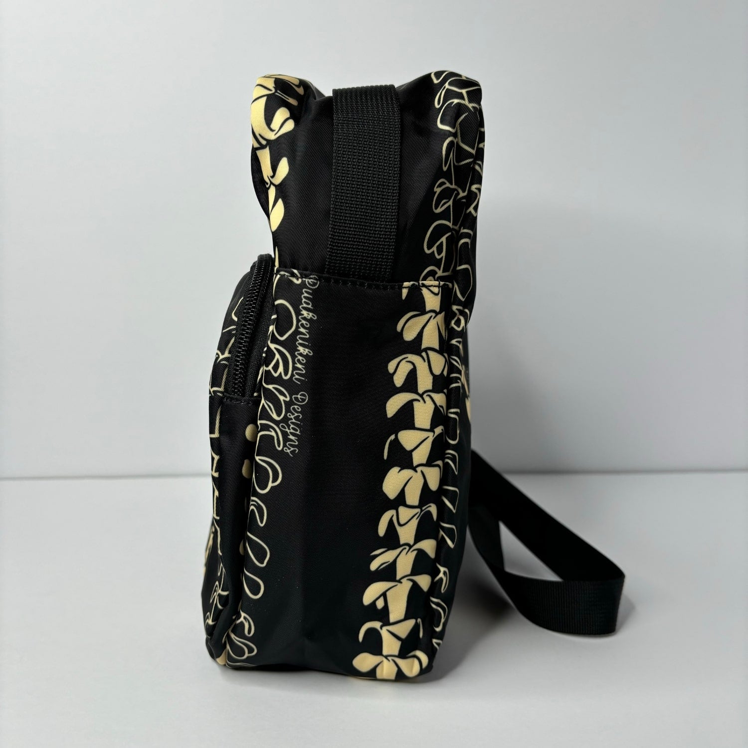 Crossbody bag by Puakenikeni Designs, in black with the best-selling pua kenikeni lei design, Kaulua; for women, moms, teenage girls, for travel and school Beige Lei Design side view