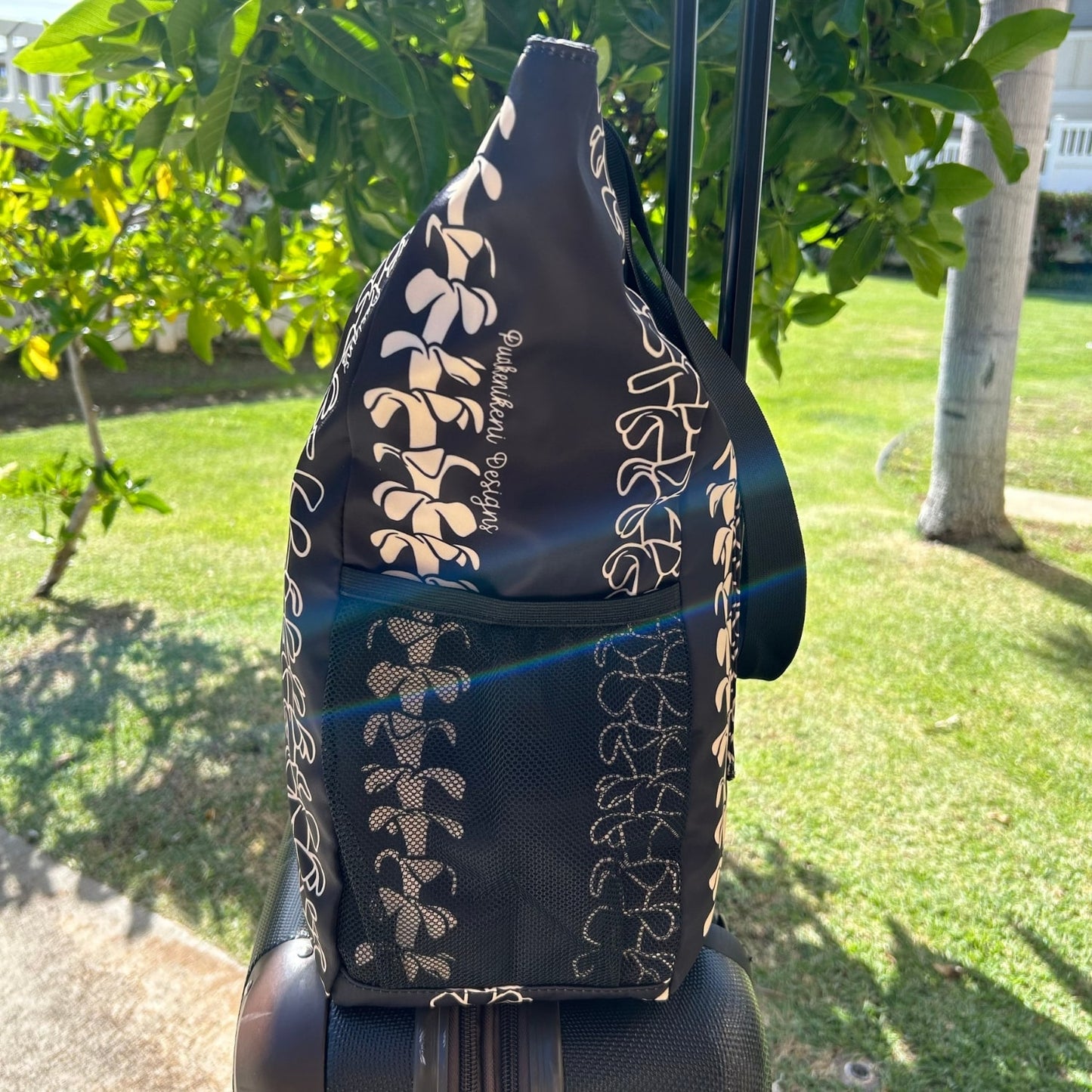 Holoholo Bag for travel from Puakenikeni Designs - use for beach, diaper bag, handbag, hula bag on a rolling suitcase side view