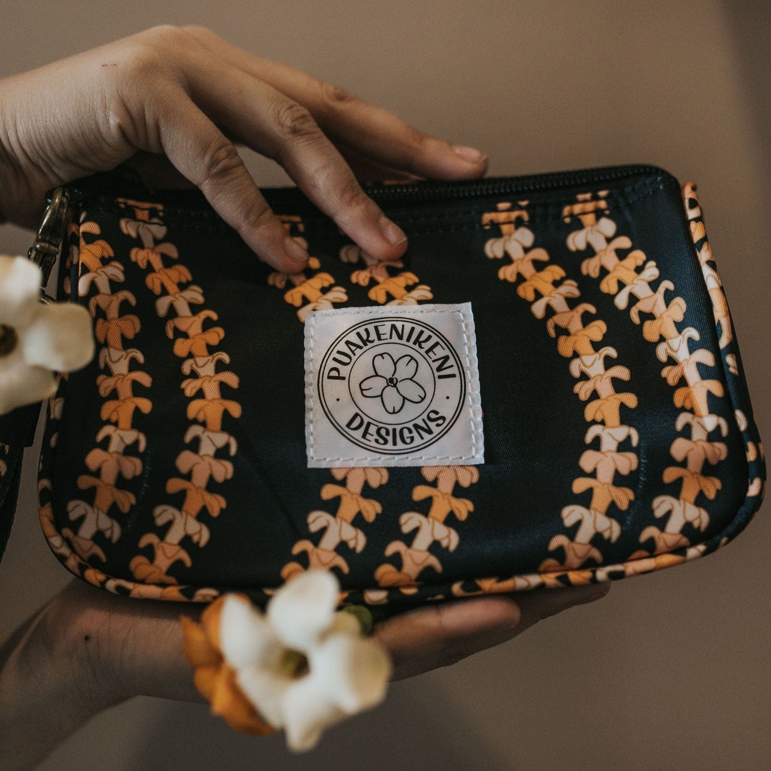 grab and go set includes mini zipper pouch and wristlet key fob in kaulua black orange lei - from Puakenikeni Designs - model holding with pua kenikeni flowers