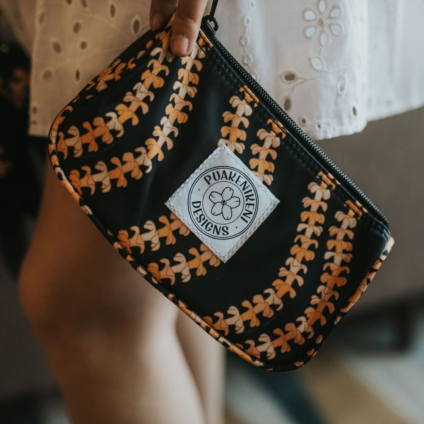 grab and go set includes mini zipper pouch and wristlet key fob in kaulua black orange lei - from Puakenikeni Designs - model holding on the side