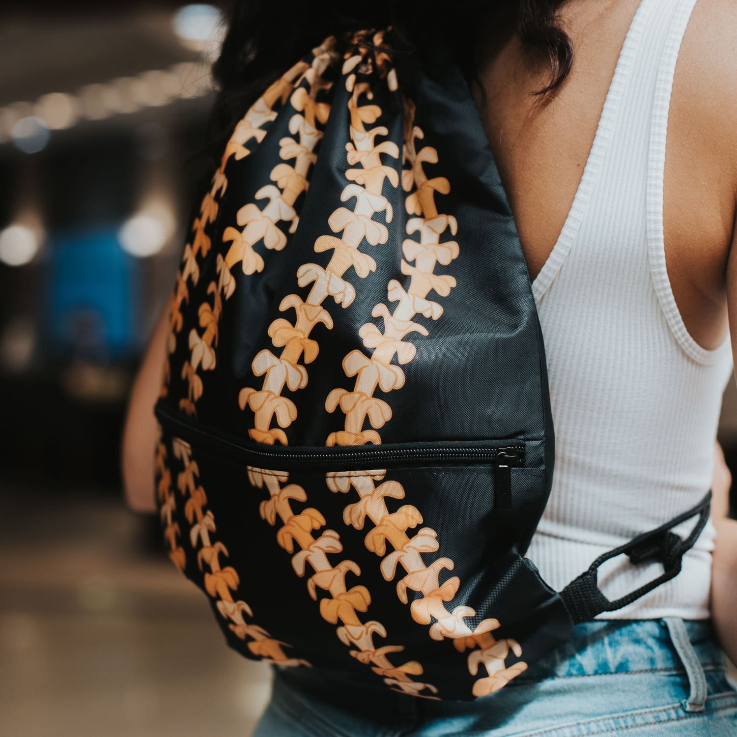 cinch drawstring backpack with pua kenikeni lei from Puakenikeni Designs Kaulua Black close up on model