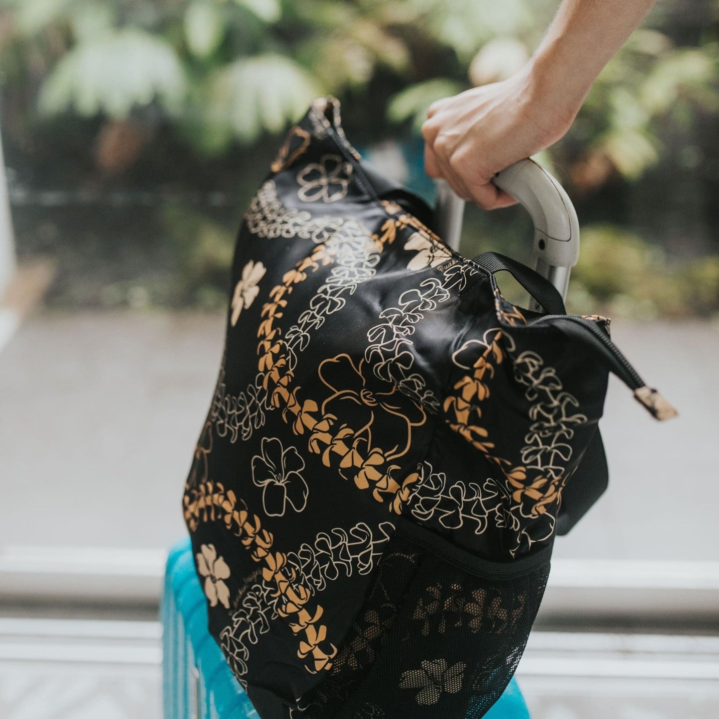 Holoholo bag with orange pua kenikeni lei from Puakenikeni Designs on luggage for travel