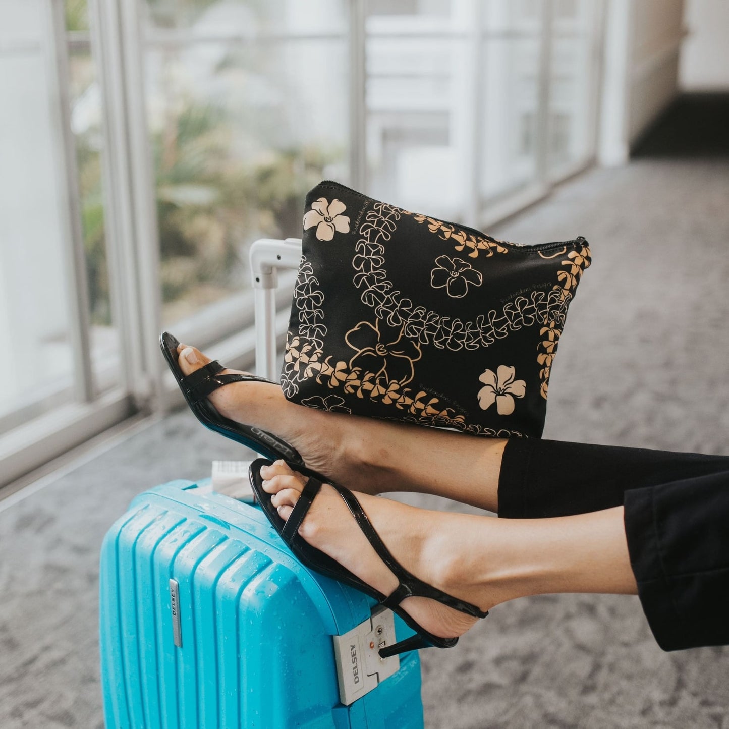 large canvas zipper pouch with orange pua kenikeni lei and flowers from Puakenikeni Designs close up on model's leg during travel