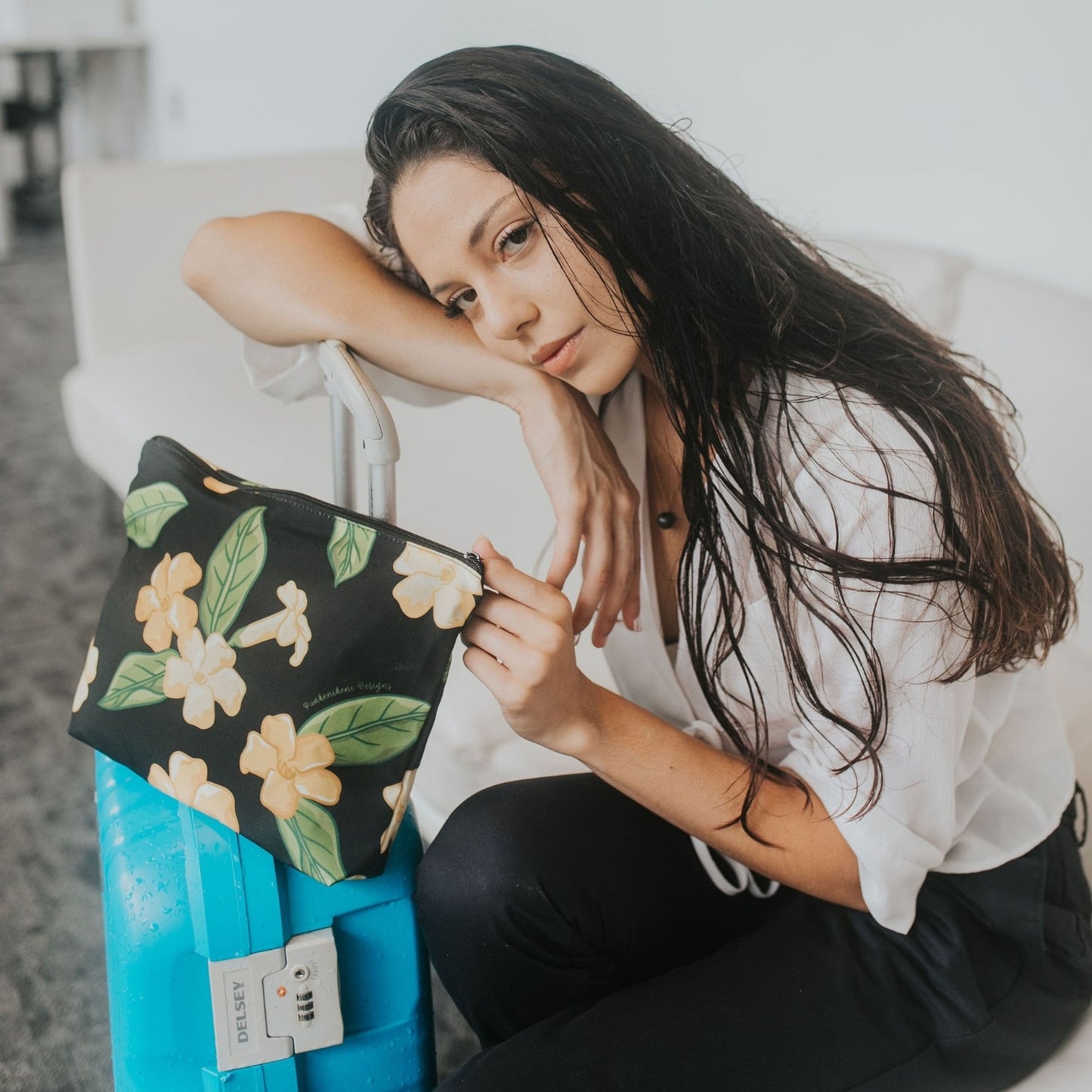 large canvas zipper pouch with pua kenikeni flowers and leaves from Puakenikeni Designs model holding on luggage during travel