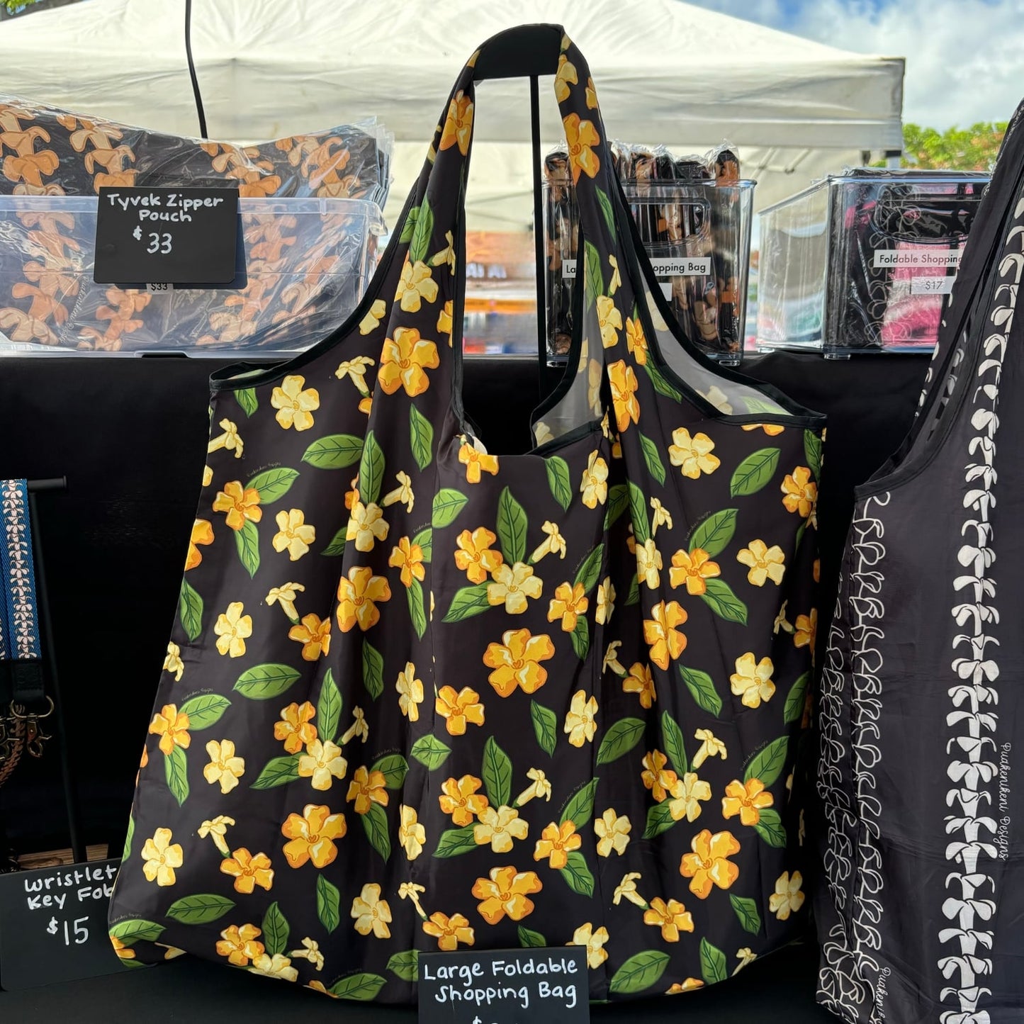 large foldable reusable shopping bag with puakenikeni flowers and leaves from Puakenikeni Designs display at What the Truck event at Waikele Center