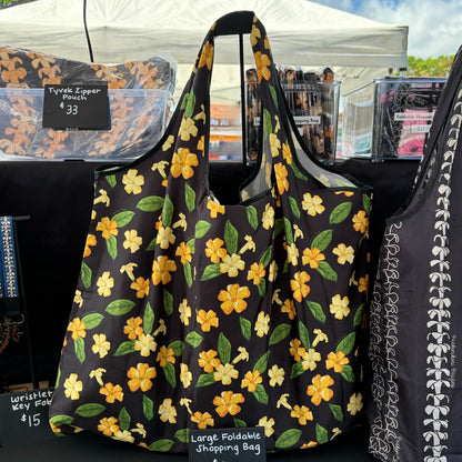 large foldable reusable shopping bag with puakenikeni flowers and leaves from Puakenikeni Designs display at What the Truck event at Waikele Center