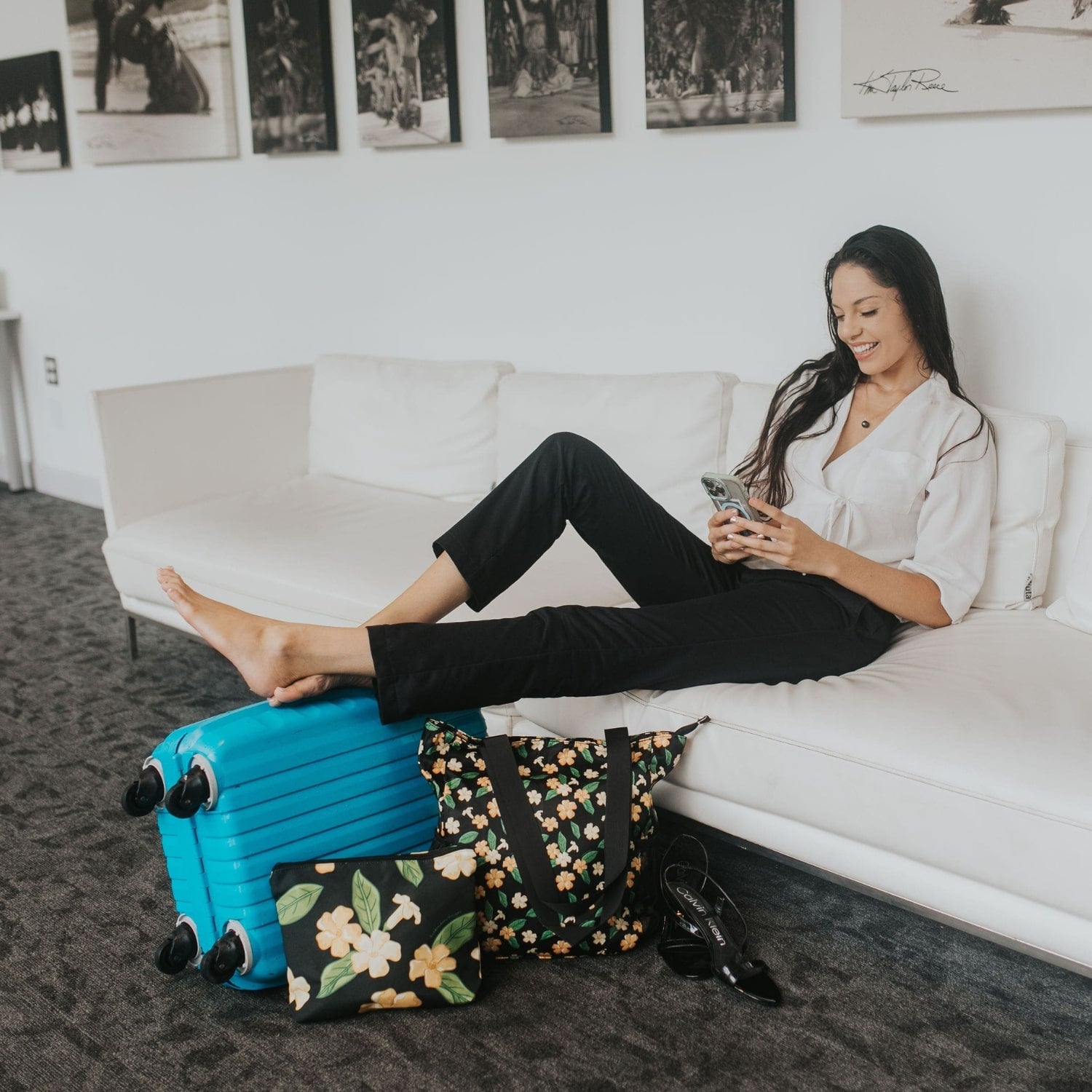 Travelers set with Holoholo Bag and Large Canvas Zipper Pouch with pua kenikeni flowers and leaves from Puakenikeni Designs model relaxing on couch in hotel lobby during travel