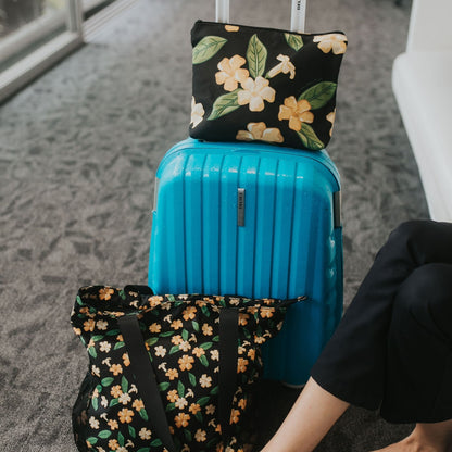 Travelers set with Holoholo Bag and Large Canvas Zipper Pouch with pua kenikeni flowers and leaves from Puakenikeni Designs model relaxing in hotel lobby during travel